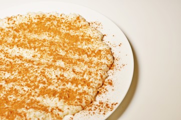 Milk with rice and cinnamon on white plate with copy text