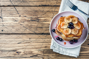 Pancake cake with bananas and berry syrup, selective focus, dark background. Copy space