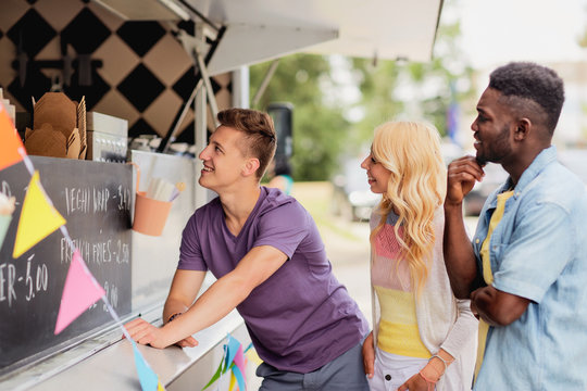 street sale and people concept - happy customers queue or friends at food truck