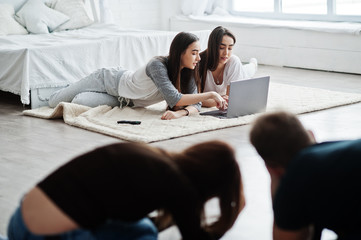 Fototapeta premium The team of two photographers shooting on studio at knees two twins models who are looking at the laptop. Professional photographer on work. Master class.