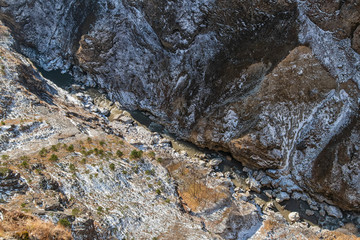 The view from the top of the cliff down into a ravine, through which flows a mountain river