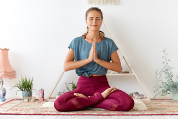 mindfulness, spirituality and healthy lifestyle concept - woman meditating in lotus pose at yoga...