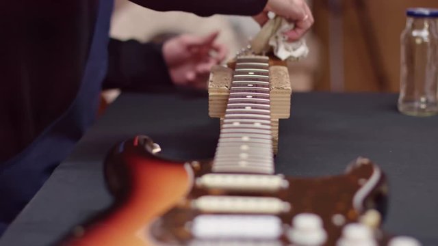 Luthier clean an electric guitar, slow motion