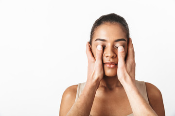 African woman posing isolated over white wall background while someone's hands covering her eyes.