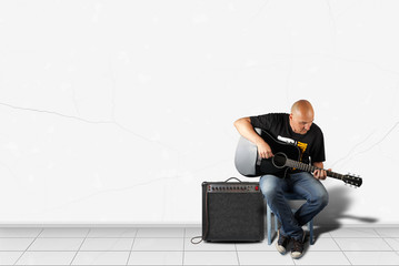 Fototapeta na wymiar Home interior - Man play a black acoustic guitar and amplifier of white wall