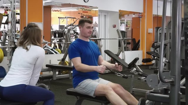 Female trainer showing newbie weightloss Back Top Lower workout exercise on bar machine in gym
