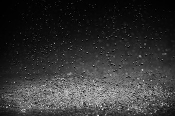 Raindrops are breaking on the surface on a black background.
