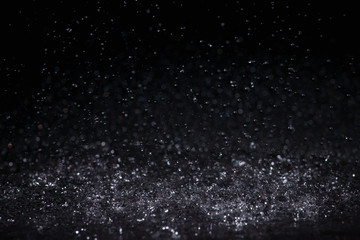 Raindrops are breaking on the surface on a black background.
