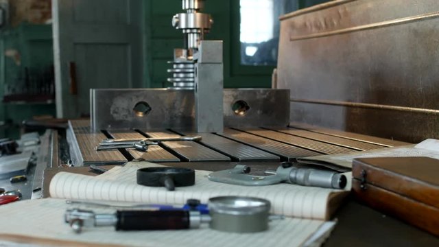 A private workshop for working with metal parts, in the background a drilling machine drills a hole in the pulley, on the table lie measuring tools, production, small business