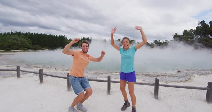 New Zealand happy tourist couple jumping happy having fun at famous attraction travel destination. Champagne pool, Waiotapu. Active geothermal area, in Taupo Volcanic Zone, Rotorua, New Zealand.