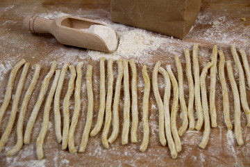 Fresh pasta fusilli homemade preparation. Homemade fresh uncooked Italian pasta with durum wheat flour on wooden background