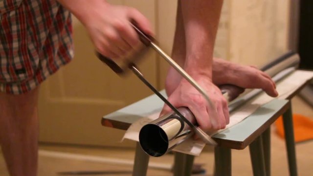 a man cuts a metal leg for the table
