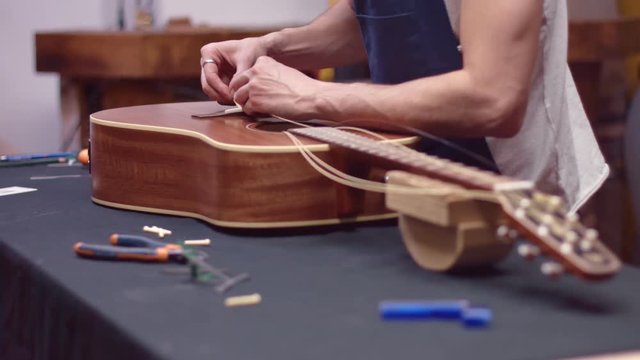 Man repairs broken guitar, slow motion