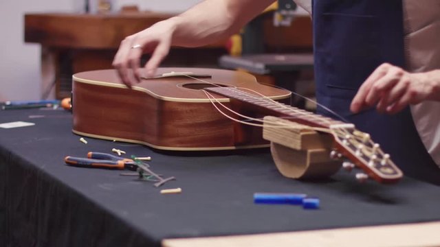 Luthier repairs guitar, changes strings
