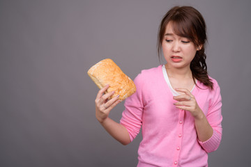 Young beautiful Asian woman holding piece of bread
