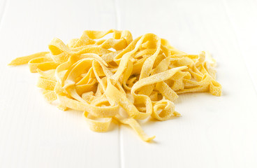 Homemade tagliatelle on wooden white background