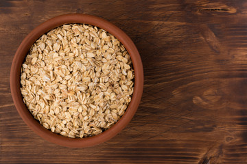 Rolled oats or oat flakes in bowl on wooden background. Healthy lifestyle, healthy eating concept. Top view