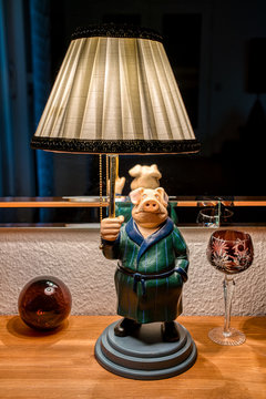 Wohndesign: leuchtende Tischlampe mit Stoffschirm in Form eines Schweins mit Spiegel im Hintergrund