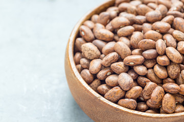 Dry pinto beans in wooden bowl, copy space, horizontal