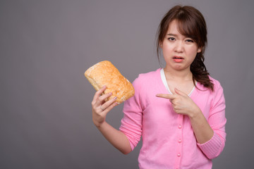 Young beautiful Asian woman holding piece of bread