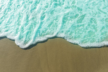 Fototapeta na wymiar White foam on a sandy beach with copy space.Soft Wave Of Blue Ocean.