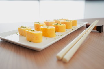 Tamagoyaki. Japanese rolled omelet with sliced coriander on white plate. Set with chopsticks.