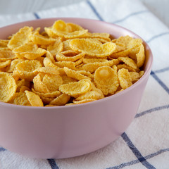Corn flakes in a pink bowl for breakfast, side view. Closeup.