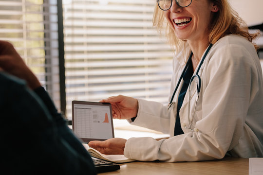 Female Doctor Showing Test Results To Patient And Smiling