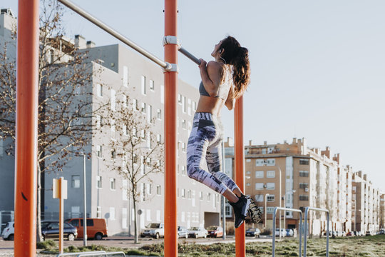Woman exercising on parallel bars in city