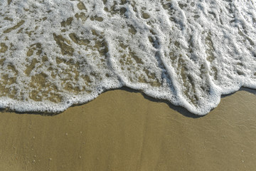Fototapeta na wymiar White foam on a sandy beach with copy space.Soft Wave Of Blue Ocean.