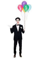 smiling clown in suit and black beret holding helium balloons isolated on white