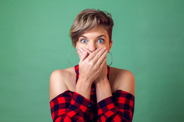 People and emotions - a portrait of surprised woman with short dark hair closed her mouth with hands