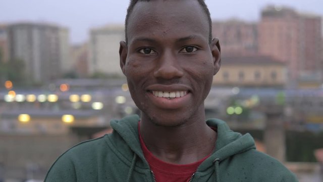 happy Attractive young african migrant smiling at camera- city in background
