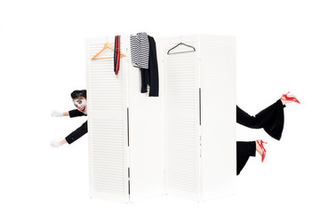 cropped view of funny clowns looking out from dressing room door isolated on white