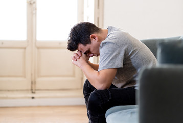 Young man suffering from depression lying on sofa alone at home feeling frustrated and hopeless