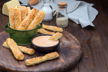 Homemade savory bread sticks with cheese and sesame in a basket, on wooden table, horizontal, copy space