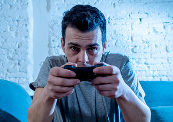 Fototapeta premium Close up portrait of young man playing video game at night addicted to it