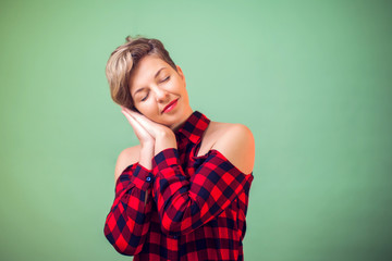 People and emotions -a portrait of smiling woman with short hair sleeping tired dreaming and posing with hands together while smiling with closed eyes.