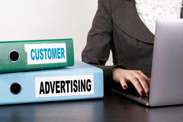 Customer and Advertising concept. Two binders on desk in the office. Business woman with laptop