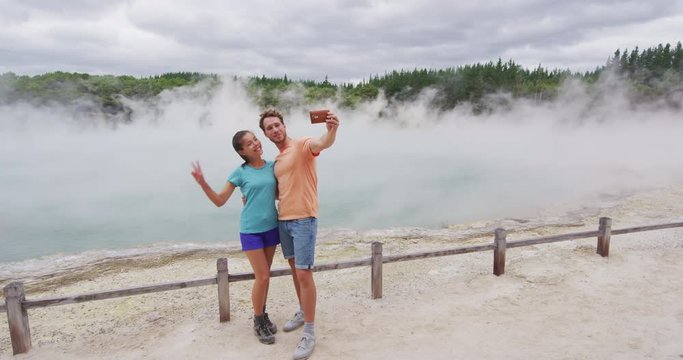 New Zealand tourist attraction couple tourists taking selfie travel destination, Waiotapu. Active geothermal famous attraction Champagne pool, Okataina Volcanic Centre, Reporoa, in Taupo Volcanic Zone