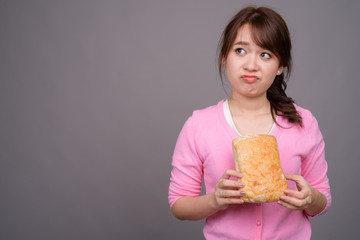 Young beautiful Asian woman holding piece of bread