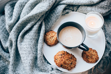 Scandinavian style breakfast, cup of coffee and cookies on cozy windowsill with warm blanket and pillow