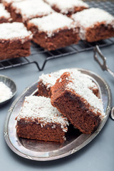 Fototapeta na wymiar Homemade brownie with coconut flakes, swedish dessert Karleksmums, cut in square servings, vertical