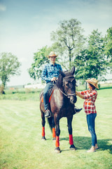Couple riding a horse in the farm in cowboy style. Sport, happiness, hobby concept