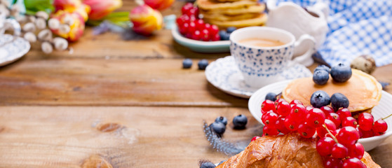 croissant with currant and blueberry berries, fresh aromatic coffee on a wooden table. Continental breakfast with fresh sweet pastries. Free space for text.