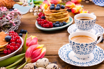 Fresh aromatic coffee in a vintage cup, homemade pastries for breakfast with blueberries and currants, on a wooden background and spring tulips. Free space for text.