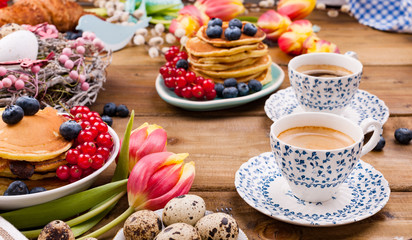 Fresh morning coffee and pastries homemade for breakfast. Pancakes with berries for a romantic breakfast and spring flowers. The concept for Easter and home comfort.