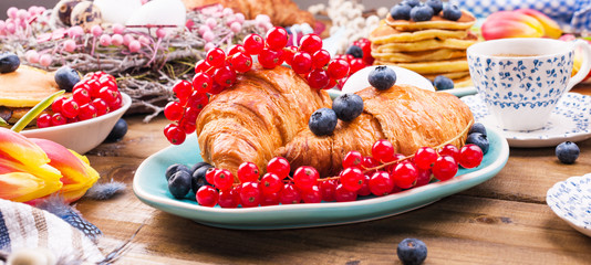 Fresh morning coffee and pastries homemade for breakfast. Delicious food for a romantic breakfast and spring flowers. The concept for Easter and home comfort.