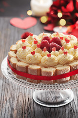 Cake with butter cream and fresh raspberries for Valentine's Day or mother's day on black wooden background,
