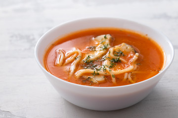 fish soup in the white bowl on ceramic background